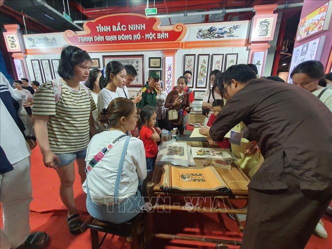 Người dân tới xem và trải nghiệm ở gian trưng bày tranh dân gian Đông Hồ-Mộc bản (Bắc Ninh) tại Trung tâm Hội chợ Triển lãm quốc gia (Đông Anh, Hà Nội), ngày 7/9. Ảnh: Nguyễn Trọng Lịch- TTXVN

