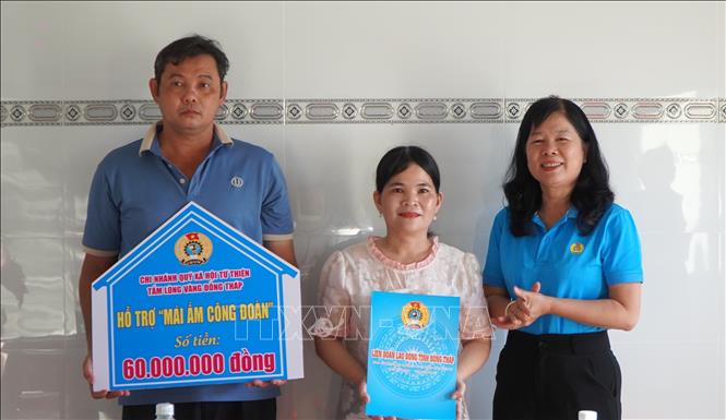 Chủ tịch LĐLĐ tỉnh Đồng Tháp Huỳnh Thị Tuyết Vui (phải) trao bảng tượng trưng hỗ trợ 60 triệu đồng xây dựng “Mái ấm Công đoàn” cho gia đình công đoàn viên Trần Thị Thùy Dương, công tác tại Trường Mầm non Phong Mỹ. Ảnh: Nhựt An - TTXVN 
