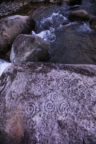 Khối đá có 4 cụm khắc với vòng tròn đồng tâm và hình gợi nhớ đến mặt khỉ, mõm lợn…, là biểu tượng được thờ cúng cách ngày nay một vài ngàn năm liên quan đến tín ngưỡng nông nghiệp trồng lúa nước của các thế hệ cư dân bản địa. Ảnh: Trọng Đạt-TTXVN