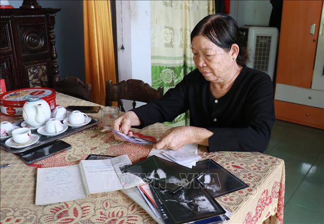 Bà Nguyễn Thị Thu xem lại những bức ảnh của tác giả Đoàn Công Tính về một thời oanh liệt của quân và dân Quảng Trị. Ảnh: Tường Vi - TTXVN