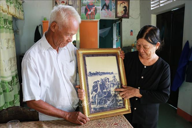 Bà Nguyễn Thị Thu cùng chồng là ông Nguyễn Câu xem lại bức ảnh chụp bà và bố chồng xuôi dòng Thạch Hãn đưa bộ đội sang sông. Ảnh: Tường Vi - TTXVN