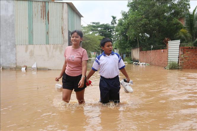 Học sinh tại phường Phước Tân, tỉnh Đồng Nai, phải lội nước đi học khi nước lũ gây ngập hết các tuyến giao thông. Ảnh: Lê Xuân-TTXVN