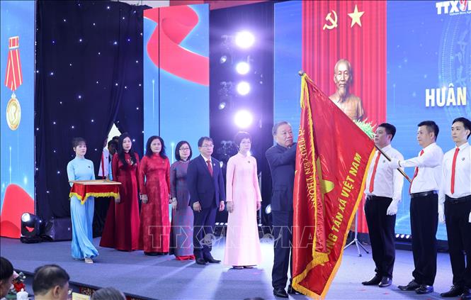 Tổng Bí thư Tô Lâm gắn Huân chương Hồ Chí Minh lên lá cờ truyền thống Thông tấn xã Việt Nam. Ảnh: Lâm Khánh - TTXVN
