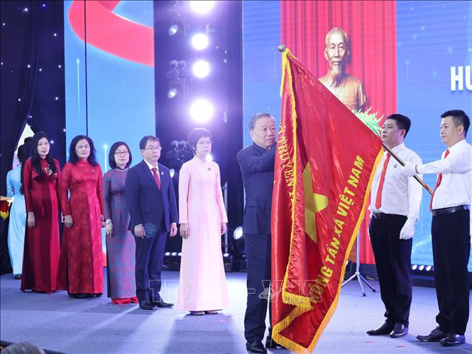 Tổng Bí thư Tô Lâm gắn Huân chương Hồ Chí Minh lên lá cờ truyền thống Thông tấn xã Việt Nam. Ảnh: Lâm Khánh - TTXVN