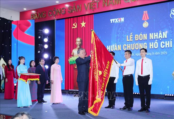 Tổng Bí thư Tô Lâm gắn Huân chương Hồ Chí Minh lên Cờ truyền thống của TTXVN. Ảnh: Trọng Đức - TTXVN