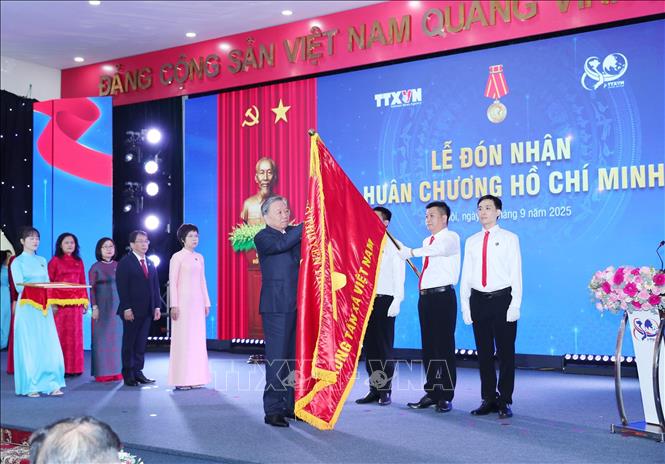 Tổng Bí thư Tô Lâm gắn Huân chương Hồ Chí Minh lên Cờ truyền thống của TTXVN. Ảnh: Trọng Đức - TTXVN