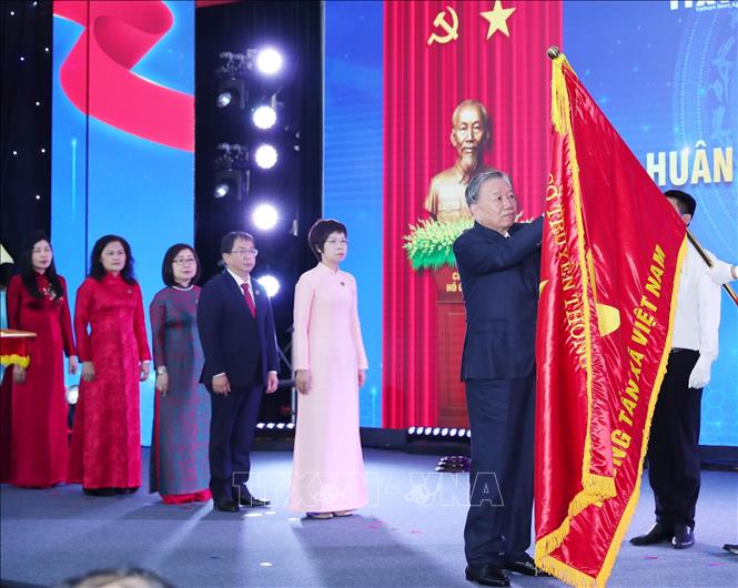 Tổng Bí thư Tô Lâm gắn Huân chương Hồ Chí Minh lên Cờ truyền thống của TTXVN. Ảnh: Trọng Đức - TTXVN