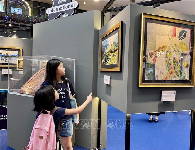 Những khán giả nhí thưởng thức tranh của nghệ sỹ khuyết tật Việt Nam trưng bày tại khu triển lãm. Ảnh: Đỗ Vân- PV TTXVN tại Singapore
