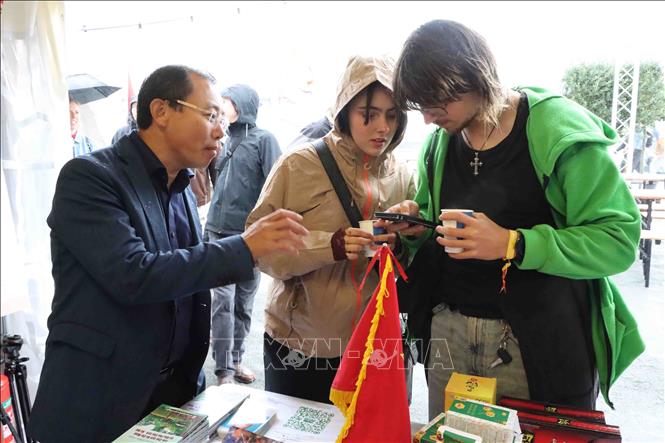 Du khách được cán bộ Đại sứ quán Việt Nam hướng dẫn quét QR để xem triển lãm trực tuyến về Chủ tịch Hồ Chí Minh. Ảnh: Hương Giang - PV TTXVN tại Bỉ