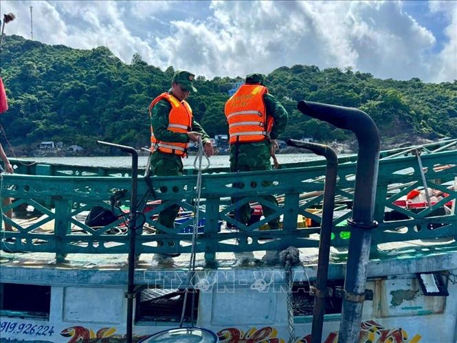 Cán bộ, chiến sĩ Đồn Biên phòng Hòn Chuối hỗ trợ trục vớt tàu cá. Ảnh: TTXVN phát