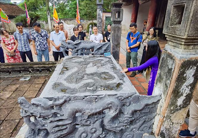 Long sàng (trước Bái đường đền thờ vua Đinh Tiên Hoàng) với điểm nhấn đặc biệt ở chi tiết chạm khắc rồng là ba trong bốn chi được điêu khắc nhân hóa mang hình dáng cánh tay và bàn tay con người. Được tạo thế khoanh mình kết hợp với những họa tiết khác thường, nhưng hình ảnh rồng cuộn trên mặt long sàng vẫn thể hiện được sự uy nghi, hùng dũng và mở ra nhiều liên tưởng nghệ thuật độc đáo. Ảnh: Thanh Tùng - TTXVN