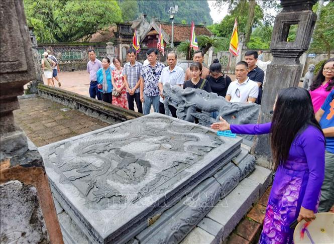 Hướng dẫn viên giới thiệu tới du khách về những nét độc đáo, tinh hoa trong nghệ thuật khắc chạm trên Bảo vật quốc gia “Long sàng”. Ảnh: Thanh Tùng - TTXVN