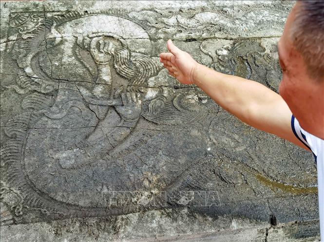 Giữa long sàng (trước Nghi môn ngoại đền thờ vua Đinh Tiên Hoàng) trang trí hình rồng cuộn mang đầy đủ nét đặc trưng của rồng thời Lê - Trịnh. Thân rồng uốn kiểu yên ngựa, đầu to, bờm lớn ngược ra phía sau, miệng há to ngậm viên ngọc châu, răng nanh sắc nhọn, sừng hai chạc, đuôi rồng vuốt về phía sau uy nghi. Bề mặt của long sàng được tạc nổi hình con rồng với dáng vẻ uy dũng, 2 tay vịn là 2 con rồng dáng vẻ thanh cao đang uốn mình trên tầng mây. Ảnh: Thanh Tùng - TTXVN