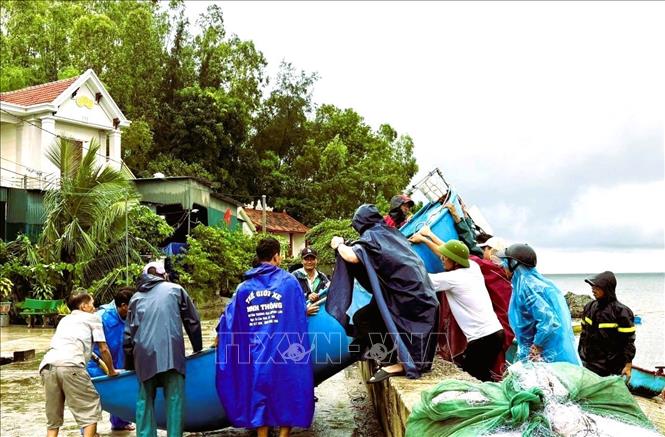 Ngư dân đẩy thuyền nhỏ và ngư lưới cụ lên bờ đê để tránh trú bão. Ảnh: TTXVN phát 