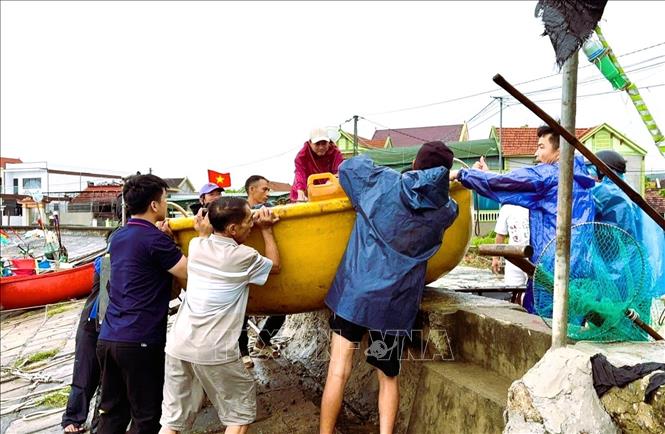 Ngư dân đưa thuyền mủng và ngư lưới cụ lên bờ đê để tránh trú bão. Ảnh: TTXVN phát 
