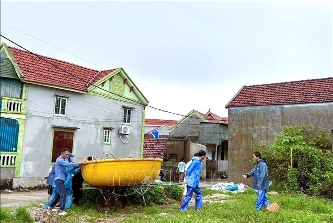 Để đảm bảo an toàn cho phương tiện trước sóng lớn, thủy triều dâng cao, ngư dân làng biển tỉnh Nghệ An đã hợp sức kéo, đẩy hàng chục thuyền nhỏ, mủng vượt qua thân đê biển, di chuyển sâu đến chỗ cao trong làng biển. Ảnh: TTXVN phát 