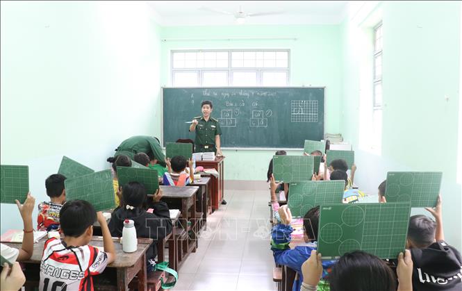 Đều đặn mỗi ngày hai ca (14 đến 16 giờ và 17 đến 19 giờ) những người thầy áo xanh tận tình chỉ từng nét chữ cho các em nhỏ. Ảnh: Bùi Giang - TTXVN