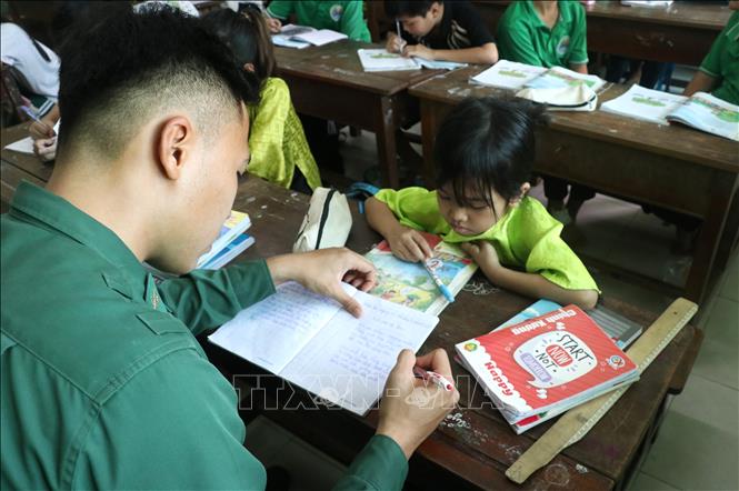 Người lính biên phòng tận tình chỉ từ nét chữ cho các em học sinh nghèo. Ảnh: Bùi Giang - TTXVN