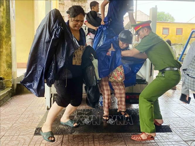 Lực lượng công an xã Đan Hải hỗ trợ đưa người dân đến nơi sơ tán. Ảnh: Hữu Quyết - TTXVN
