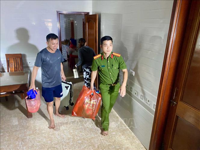 Lực lượng công an xã Đan Hải hỗ trợ đưa người dân đến nơi sơ tán. Ảnh: Hữu Quyết - TTXVN