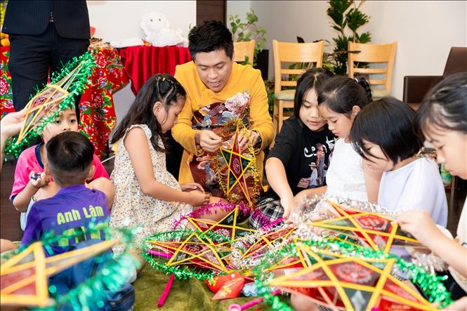 Chủ tịch Hội Người Việt Nam tại Fukuoka - Trưởng Ban tổ chức cùng các em nhỏ trải nghiệm làm đèn lồng truyền thống. Ảnh: Xuân Giao - PV TTXVN tại Nhật Bản