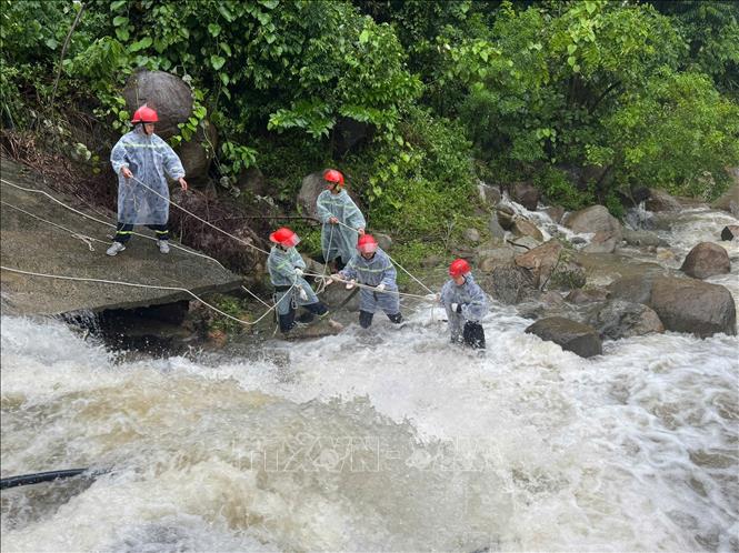 Lực lượng chức năng căng dây để trục vớt thi thể người đàn ông dưới dòng nước chảy siết. Ảnh: TTXVN phát