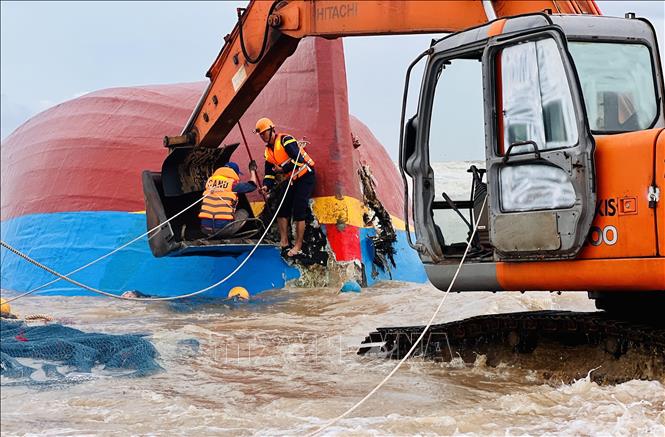 Lực lượng cứu hộ sử dụng xe múc để phá vỡ mui tàu, sau đó dùng xe cẩu chuyên dụng kéo toang các mảnh vỏ bằng dây cáp, tạo điều kiện tiếp cận khoang tàu bên trong tàu. Ảnh: Nguyên Linh-TTXVN