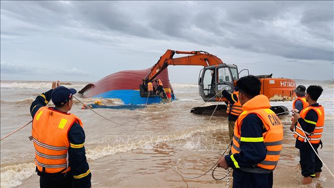Lực lượng cứu hộ sử dụng xe múc để phá vỡ mui tàu, sau đó dùng xe cẩu chuyên dụng kéo toang các mảnh vỏ bằng dây cáp, tạo điều kiện tiếp cận khoang tàu bên trong tàu. Ảnh: Nguyên Linh-TTXVN