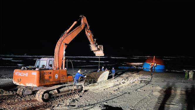 Xe máy xúc vận chuyển những tấm thép lớn để làm đường cho xe cần cẩu hạng nặng tiếp hiện trường tàu gặp nạn. Ảnh: Nguyên Linh-TTXVN