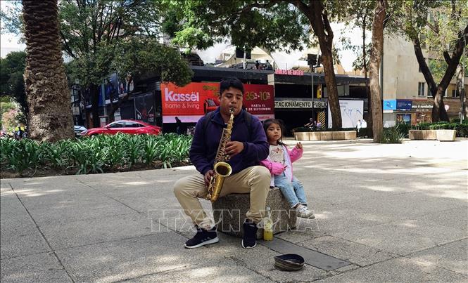 Một người đàn ông biểu diễn saxophone để xin tiền tại đại lộ Reforma, trung tâm thủ đô Mexico City, Mexico. Ảnh: Phi Hùng - PV TTXVN tại Mexico