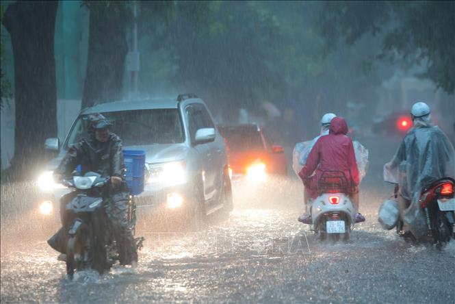 Mưa xối xả khiến phố Hàng Bài ngập nặng, ô tô phải bật đèn khi di chuyển. Ảnh: Hoàng Hiếu - TTXVN