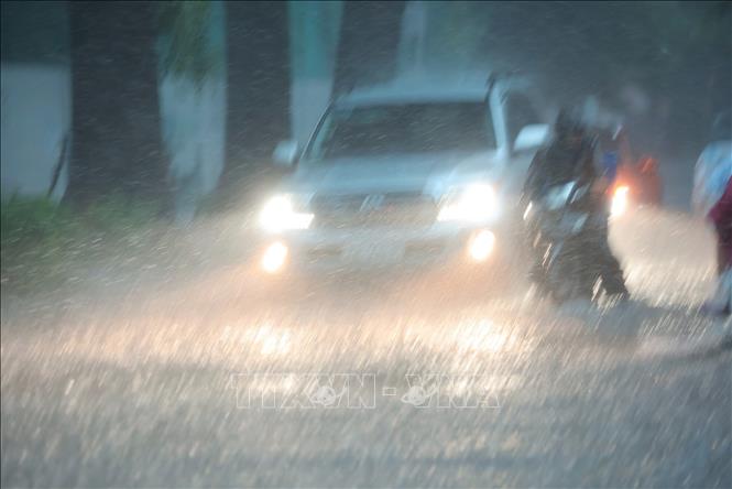 Mưa xối xả khiến phố Hàng Bài ngập nặng, ô tô phải bật đèn khi di chuyển. Ảnh: Hoàng Hiếu - TTXVN