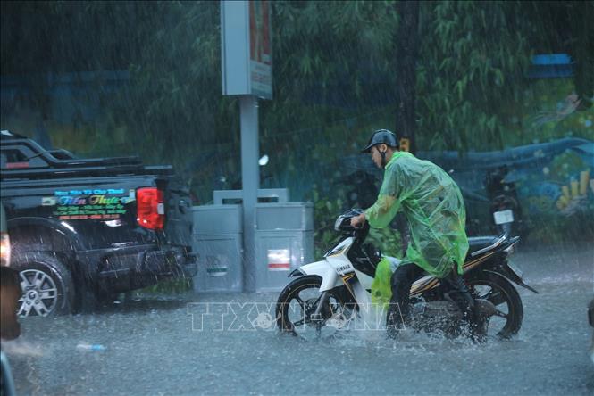 Nhiều người đi xe máy phải xuống dắt bộ vì mưa quá lớn. Ảnh: Hoàng Hiếu - TTXVN