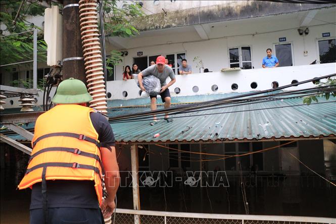 Lực lượng chức năng hỗ trợ người dân di chuyển đến nơi an toàn. Ảnh: Tuấn Anh - TTXVN