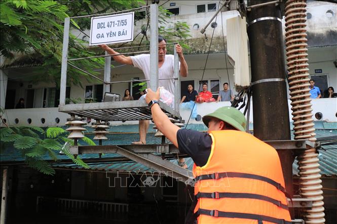 Lực lượng chức năng hỗ trợ người dân di chuyển đến nơi an toàn. Ảnh: Tuấn Anh - TTXVN