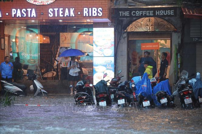 Nước ngập lên vỉa hè, mấp mé hàng quán trên phố Hàng Bài. Ảnh: Hoàng Hiếu-TTXVN