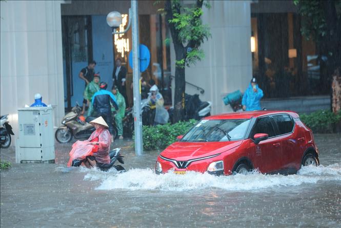 Xe điện là các phương tiện di chuyển được trong tình trạng ngập nước. Ảnh: Hoàng Hiếu - TTXVN