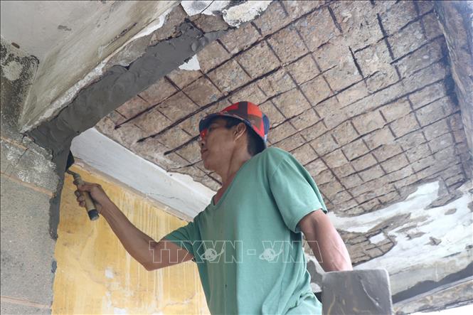Người dân sửa chữa tạm thời các trần hành lang chung cư Phạm Thế Hiển (phường Chánh Hưng) bị hư hỏng, bong tróc lòi ra cả phần thép sắt hoen gỉ để tránh rơi đỗ tiềm ẩn nhiều nguy hiểu cho cư dân sinh sống tại đây. Ảnh: Thanh Vũ-TTXVN