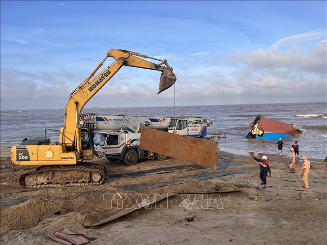 Xe máy múc vận chuyển những tấm thép lớn làm đường cho xe cần cẩu hạng nặng tiếp cận tàu bị nạn. Ảnh: Nguyên Linh-TTXVN 