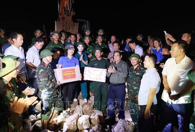 Thủ tướng Phạm Minh Chính tặng quà động viên cho các lực lượng đang gia cố đê điều, khắc phục hậu quả tại khu vực đê biển Hải Thịnh 3. Ảnh: Dương Giang-TTXVN 
