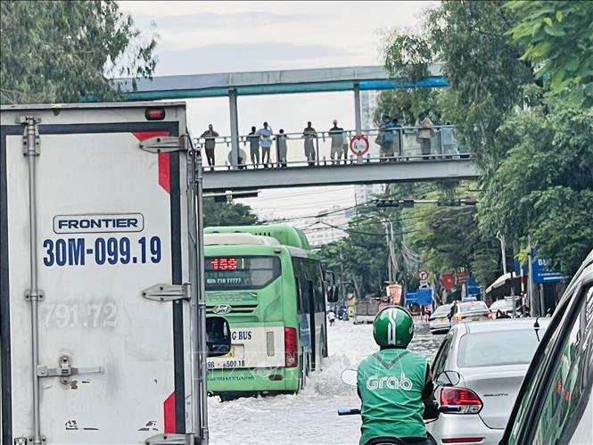 Xe buýt vẫn lưu thông qua điểm ngập trên đường Cầu Bươu. Ảnh: Tuyết Mai - TTXVN