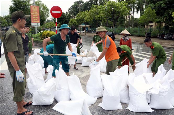 Lực lượng công an Phòng quản lý hành chính, Công an tỉnh Ninh Bình, cùng dân quân tự vệ giúp dân đắp đê tạm chống lũ trên sông Đáy. Ảnh: Nguyễn Chinh - TTXVN
