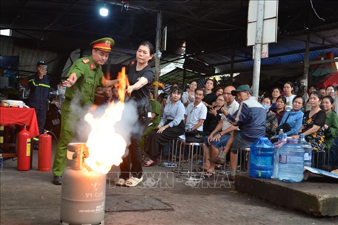 Cán bộ Phòng Cảnh sát PCCC&CNCH, Công an Thành phố Hồ Chí Minh hướng dẫn các tiểu thương cách chữa cháy khi có sự cố xảy ra. Ảnh : Linh Sơn - TTXVN