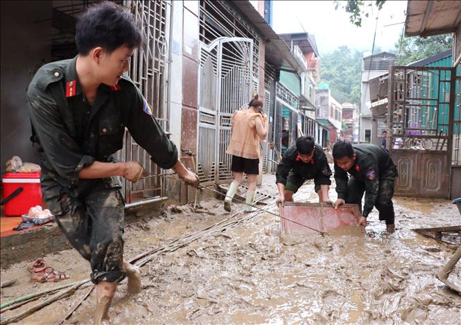 Các chiễn sĩ đồn biên phòng Cửa khẩu Quốc tế Thanh Thủy (Tuyên Quang) giúp người dân dọn vệ sinh sau lũ. Ảnh: Đức Thọ - TTXVN