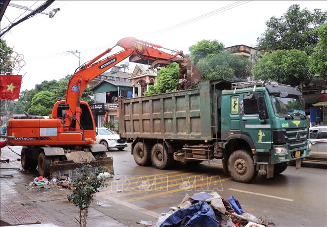 Lượng rác do lũ cuốn về quá nhiều nên phải dùng máy xúc để dọn dẹp. Ảnh: Đức Thọ - TTXVN