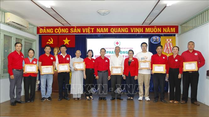 Ông Trần Văn Tuấn, Chủ tịch Hội Chữ thập đỏ Thành phố Hồ Chí Minh, trao thư cám ơn các nhà hảo tâm đăng ký và đóng góp ủng hộ đồng bào bị thiên tai ngay sau lễ phát động. Ảnh: Thanh Vũ-TTXVN