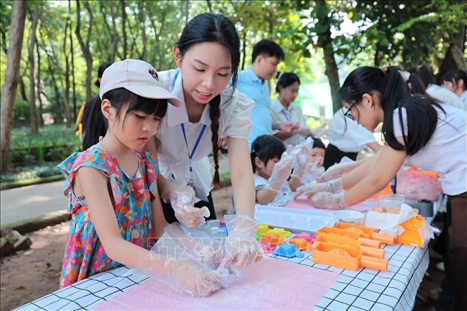 Children learns how to make sweet sticky rice moon cake at the event. VNA Photo: Lê Đông