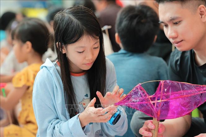 A child learns how to make carp-shaped lantern at the event. VNA Photo: Lê Đông