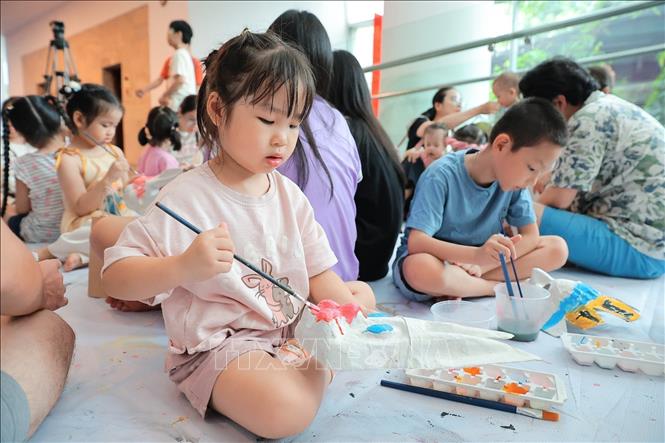 Children learn how to make and paint paper masks at the event. VNA Photo: Lê Đông