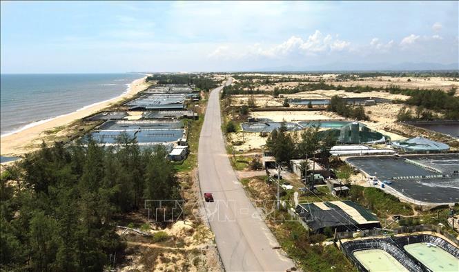 Tuyến đường ven biển đi qua khu vực hồ nuôi tôm của người dân xã Đông Trạch. Ảnh: Nguyên Linh-TTXVN
